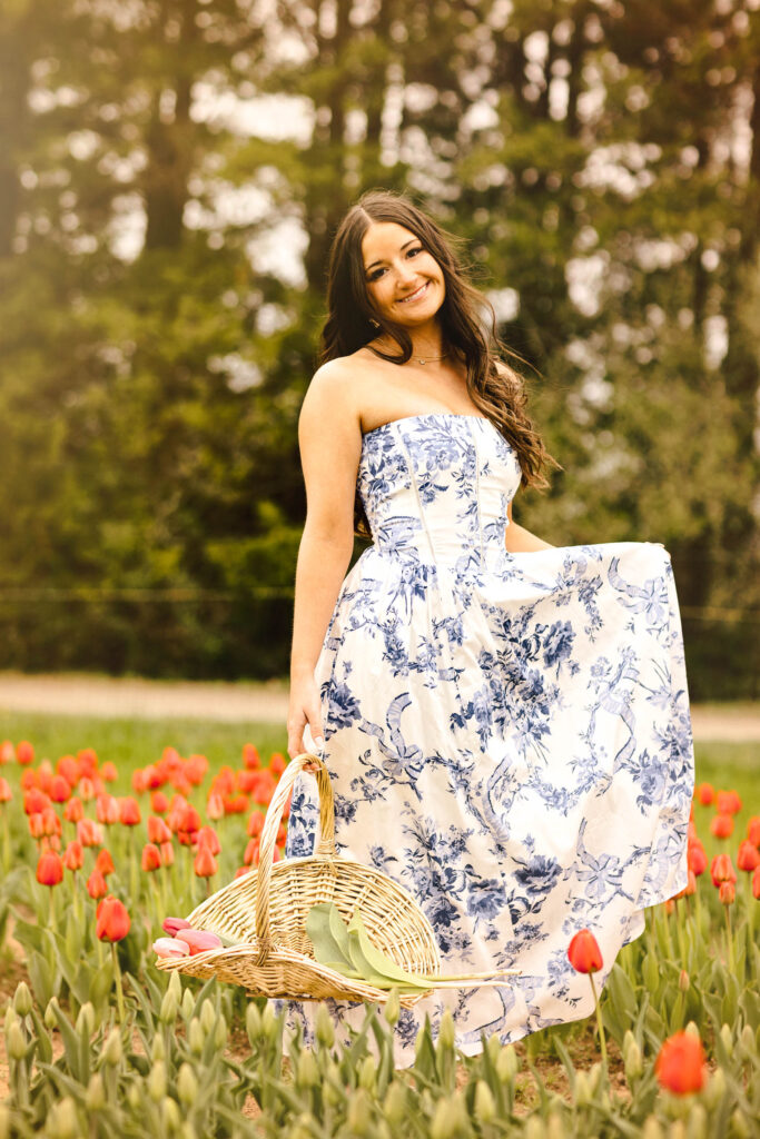 Senior portrait of a high school senior wearing a blue floral maxi dress while holding a basket in a tulip field during a senior photography session in Rhode Island with Jennifer Helmka, Photographer.