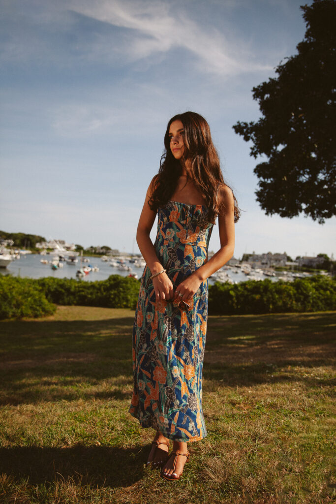 Editorial senior portrait featuring a floral maxi dress overlooking a Cape Cod Harbor during a senior photography session in Cape Cod, Massachusetts with Jennifer Helmka, Photographer.
